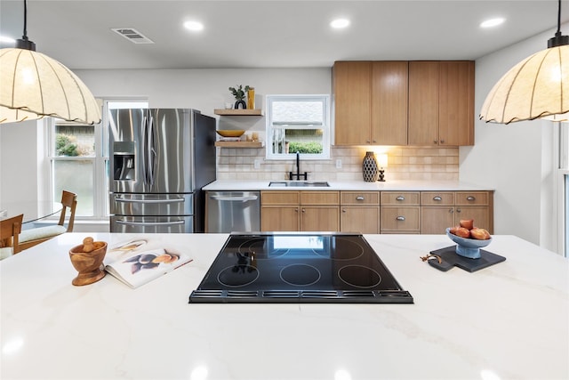 kitchen featuring stainless steel appliances, sink, backsplash, and decorative light fixtures