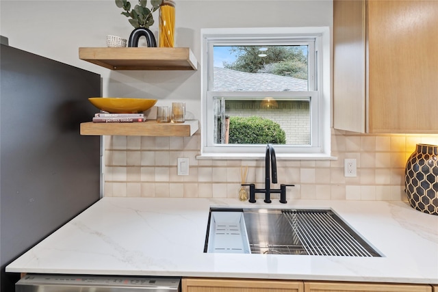 kitchen featuring sink, stainless steel dishwasher, backsplash, and light stone counters