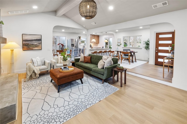 living room featuring beam ceiling, high vaulted ceiling, and light wood-type flooring