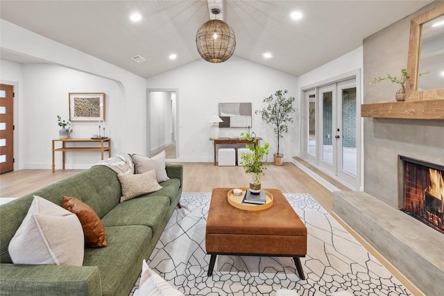 living room with french doors, lofted ceiling, a fireplace, and light wood-type flooring