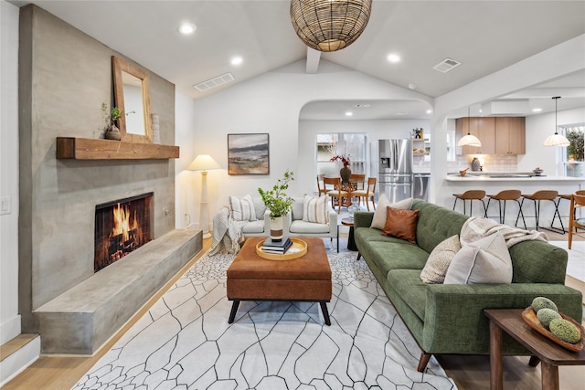 living room with a premium fireplace, lofted ceiling with beams, and light hardwood / wood-style flooring