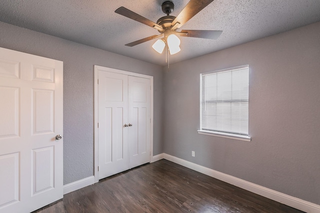 unfurnished bedroom with ceiling fan, dark hardwood / wood-style flooring, a closet, and a textured ceiling