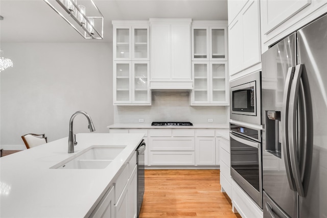 625 N Tyler St Unit 402, Dallas, TX 75208 - kitchen with light countertops, white cabinets, a sink, light wood finished floors, and stainless steel appliances
