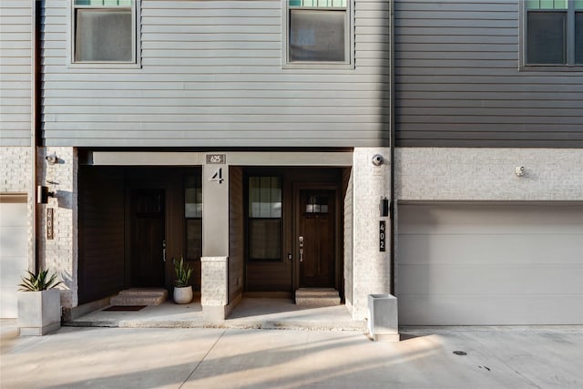 625 N Tyler St Unit 402, Dallas, TX 75208 - view of exterior entry featuring a garage, driveway, and stone siding