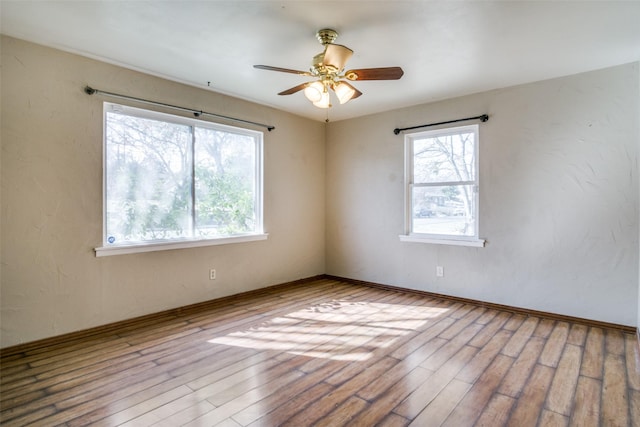 unfurnished room with a wealth of natural light, ceiling fan, and light wood-type flooring