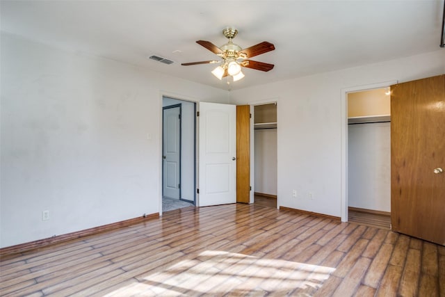 unfurnished bedroom featuring multiple closets, ceiling fan, and light hardwood / wood-style flooring