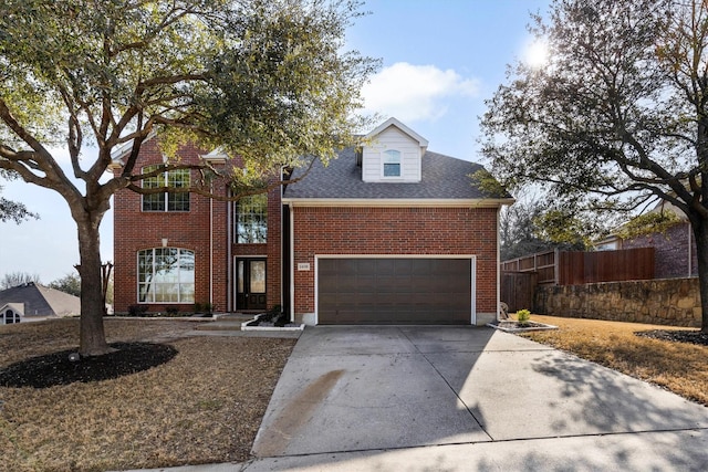 traditional-style house featuring a shingled roof, concrete driveway, brick siding, and fence