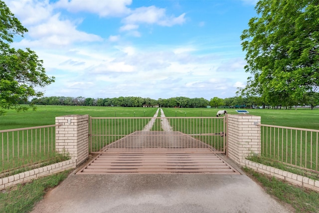 view of gate featuring a yard, a rural view, and fence