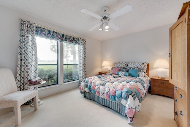 bedroom featuring a textured ceiling, a ceiling fan, and light colored carpet