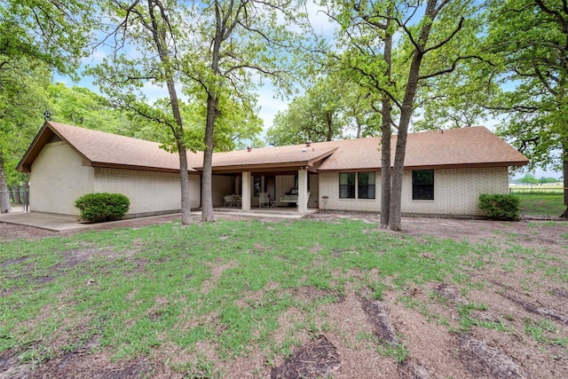 rear view of property featuring brick siding, a lawn, a patio area, and fence