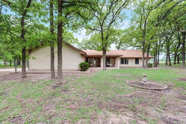 view of front of house featuring a front yard, a patio area, brick siding, and fence