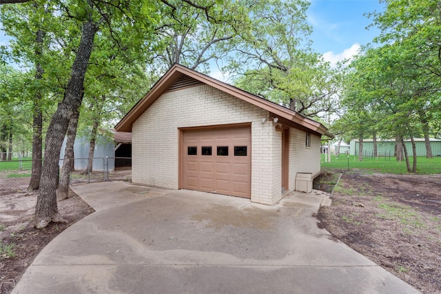 view of home's exterior featuring an outbuilding, a garage, brick siding, fence, and concrete driveway