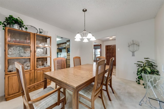 dining room with a chandelier, a textured ceiling, and light colored carpet