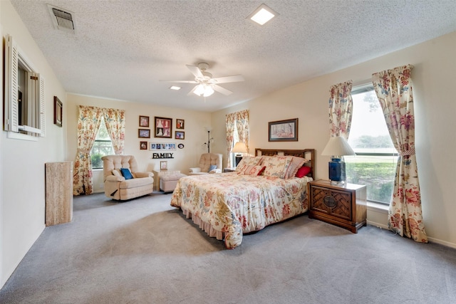 bedroom with ceiling fan, a textured ceiling, carpet flooring, and visible vents