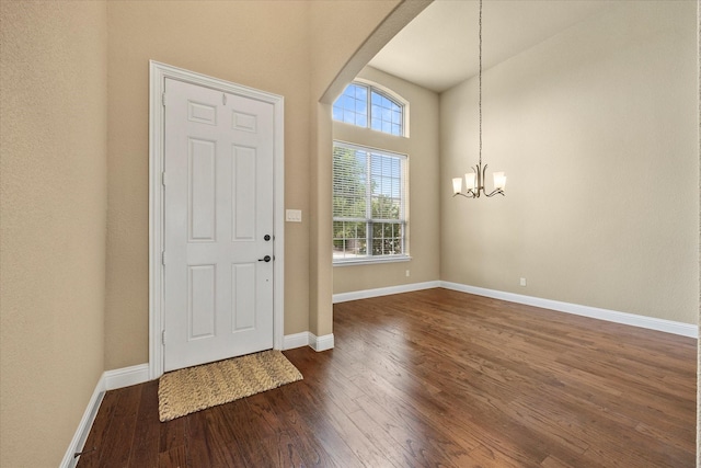 1555 Sonnet Dr, Heath, TX 75126 - empty room featuring arched walkways, a chandelier, dark wood finished floors, baseboards, and high vaulted ceiling