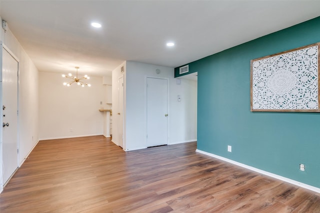 empty room featuring hardwood / wood-style flooring and a chandelier