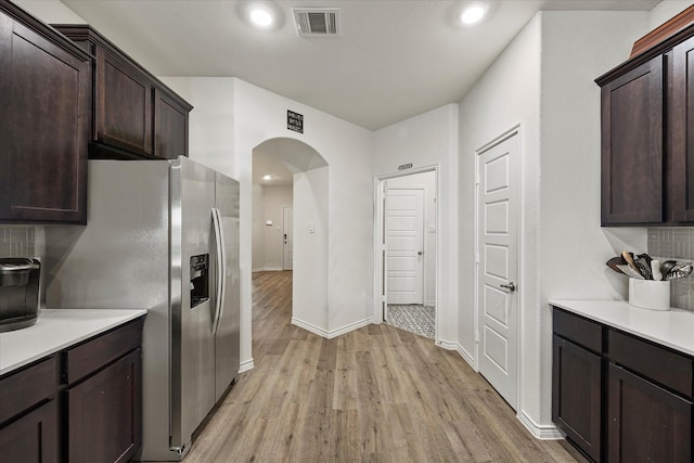 kitchen with light hardwood / wood-style flooring, stainless steel fridge with ice dispenser, backsplash, and dark brown cabinets