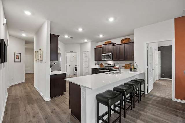 126 Condor Pass, Caddo Mills, TX 75135 - kitchen featuring appliances with stainless steel finishes, washer / clothes dryer, dark wood-type flooring, dark brown cabinetry, and recessed lighting