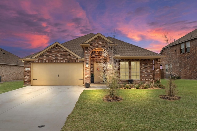 view of front of home with a front yard, roof with shingles, concrete driveway, a garage, and brick siding