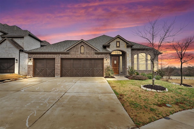 french country home featuring a garage and a lawn