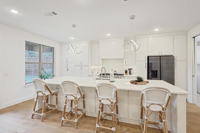 5809 Fursman Ave, Fort Worth, TX 76114 - kitchen featuring stainless steel refrigerator with ice dispenser, light countertops, a center island with sink, white cabinets, and light wood-style flooring