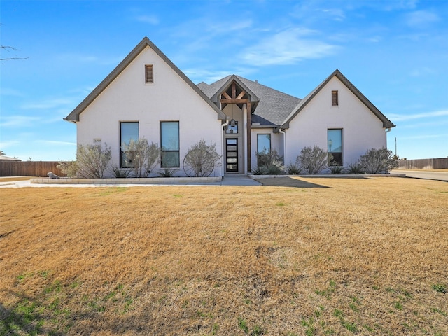 view of front of home featuring fence, a front lawn, and stucco siding