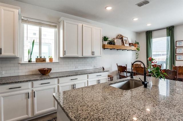 kitchen with white cabinetry, sink, decorative backsplash, and light stone counters