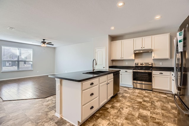 kitchen with appliances with stainless steel finishes, sink, white cabinets, a kitchen island with sink, and ceiling fan