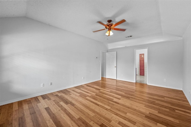 empty room featuring ceiling fan, lofted ceiling, light hardwood / wood-style floors, and a textured ceiling