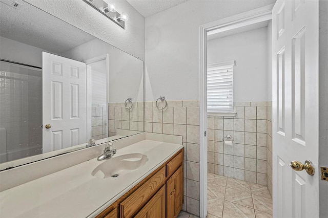 2305 Buckeye Dr, Mesquite, TX 75181 - bathroom with vanity, tile walls, a textured ceiling, wainscoting, and tile patterned flooring