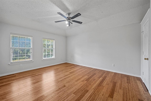 spare room with ceiling fan, lofted ceiling, hardwood / wood-style floors, and a textured ceiling