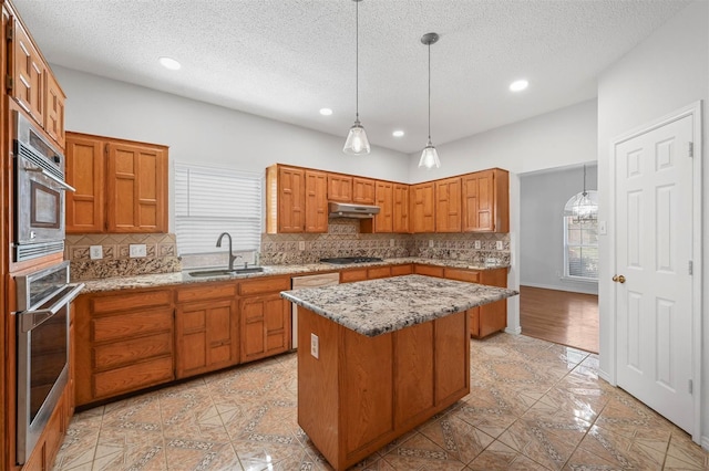 kitchen with black gas cooktop, decorative light fixtures, sink, oven, and a center island