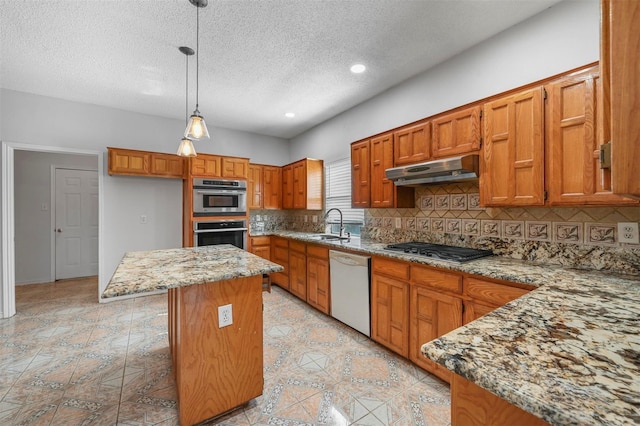 kitchen with hanging light fixtures, stainless steel appliances, a center island, tasteful backsplash, and light stone countertops