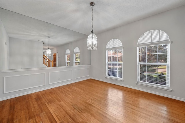 2305 Buckeye Dr, Mesquite, TX 75181 - unfurnished dining area with wood finished floors, a chandelier, and stairway