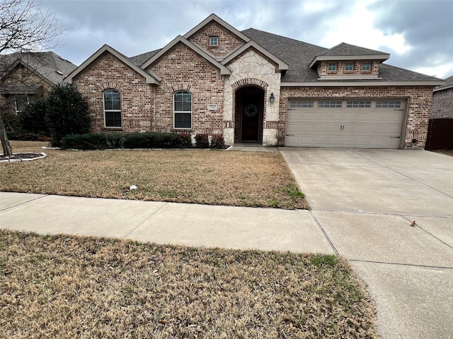 french country home with concrete driveway, brick siding, roof with shingles, and a front yard