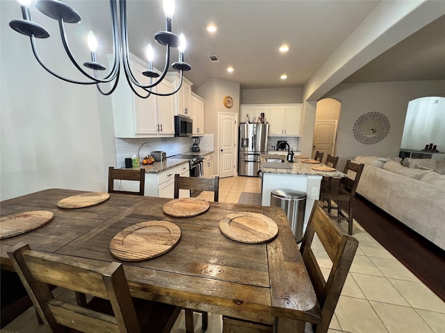 dining room with light tile patterned floors, arched walkways, visible vents, and recessed lighting