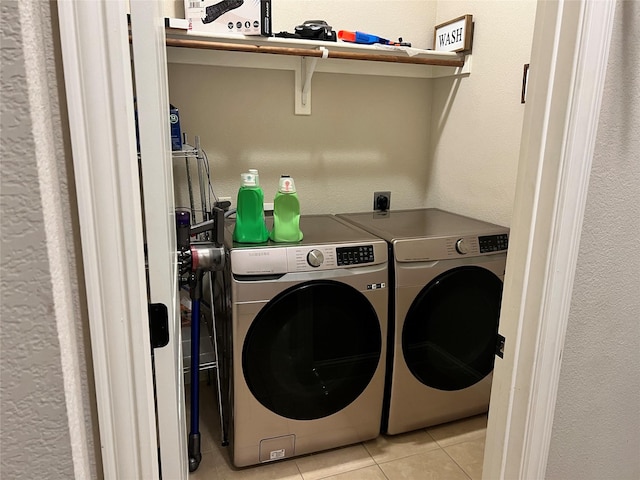 laundry area with a textured wall, laundry area, light tile patterned flooring, and washing machine and clothes dryer