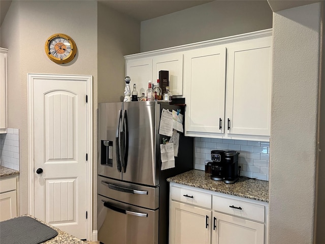 kitchen featuring stone countertops, stainless steel fridge, and white cabinets