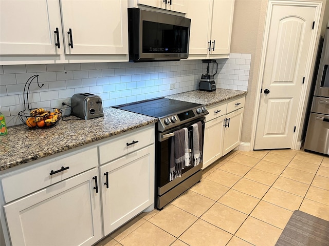 kitchen with light stone countertops, white cabinetry, and appliances with stainless steel finishes