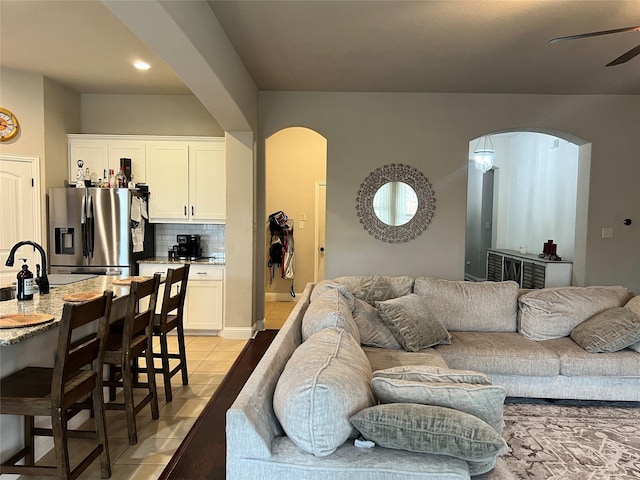 living room with arched walkways, light tile patterned floors, and a ceiling fan