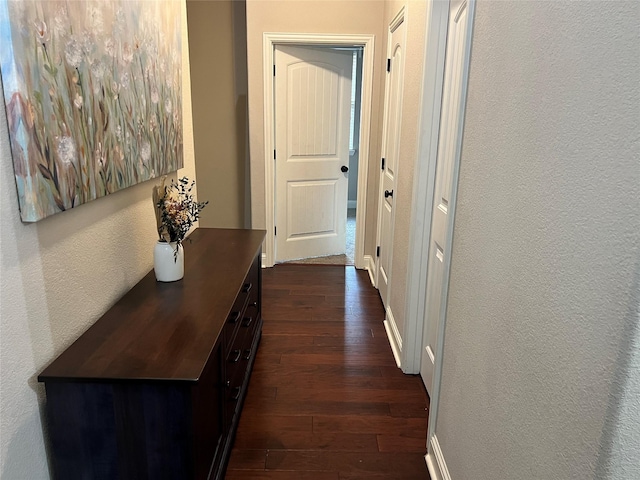 hallway with dark wood-style floors and a textured wall