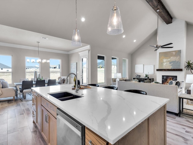 kitchen with pendant lighting, stainless steel dishwasher, an island with sink, and sink