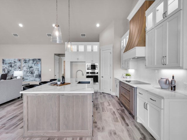 kitchen featuring a spacious island, white cabinetry, appliances with stainless steel finishes, and custom range hood