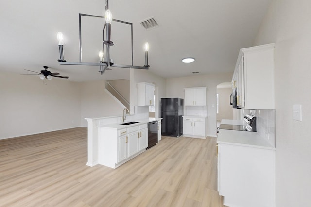 kitchen with hanging light fixtures, black appliances, sink, and white cabinets