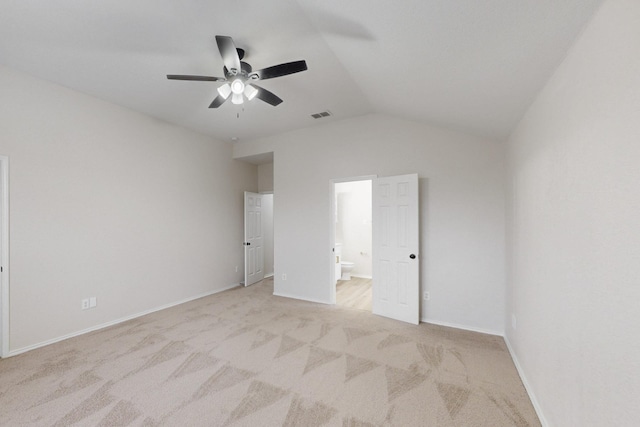 unfurnished bedroom featuring lofted ceiling, connected bathroom, light colored carpet, and ceiling fan