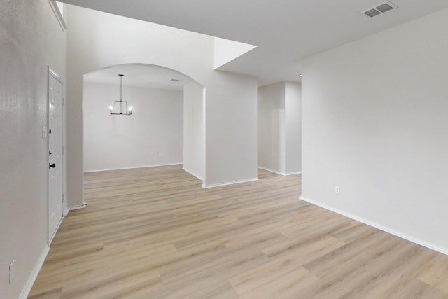 unfurnished room featuring an inviting chandelier and light hardwood / wood-style floors