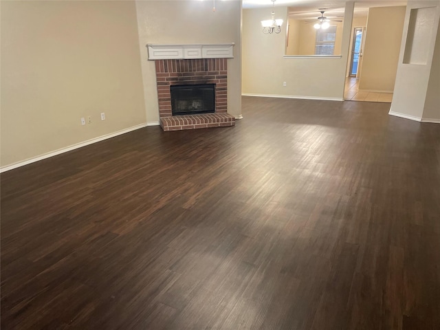 unfurnished living room with a fireplace, dark hardwood / wood-style flooring, and ceiling fan with notable chandelier