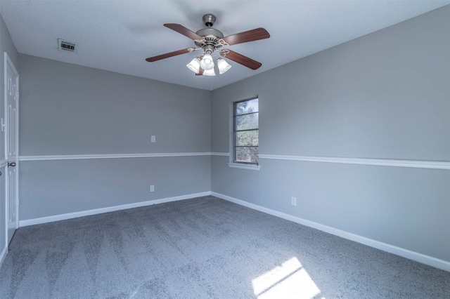 spare room featuring ceiling fan and dark colored carpet