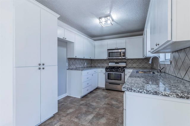 kitchen with appliances with stainless steel finishes, sink, white cabinets, ornamental molding, and light stone countertops