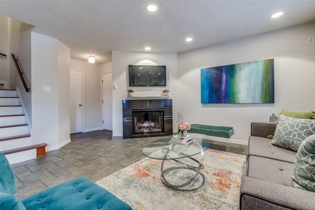 living room featuring a tile fireplace and a textured ceiling